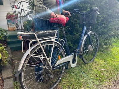 Jessica holds an electric bike upright on the grass out the front of her home.